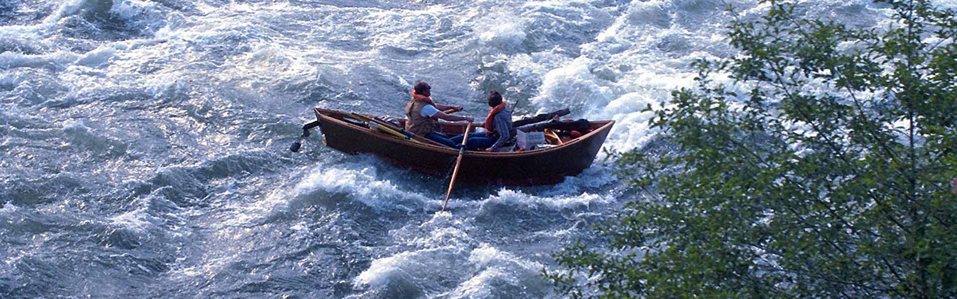 A picture of a McKenzie river dory wooden drift boat hurtling down the rapids